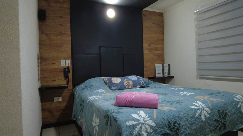 Habitación Standar con muro negro y madera, cama con cobertor floral