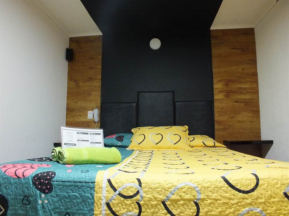 Habitación Standar con muro de madera y cobertor amarillo de lunas
